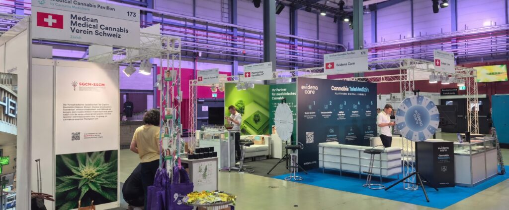 Medical Cannabis Pavilion at a trade show in Switzerland. Medcan Medical Cannabis Verein Schweiz (booth 173) and Evidena Care exhibition stands with Swiss flags, cannabis product displays, informational banners, and visitors browsing the booths.