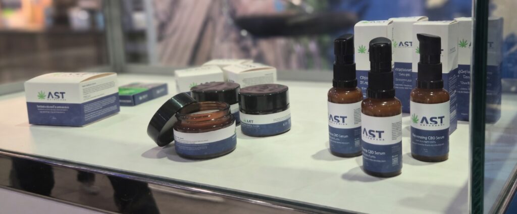 AST NaturalsのCBDスキンケア製品展示。ガラスショーケース内に並べられたCBDクリームジャー、CBDセラムボトル、商品箱