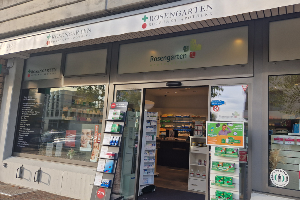 スイスのRosengarten Rotpunkt Apotheke（ローゼンガルテン薬局）の外観。ガラス自動ドアが開いており、店内の棚や商品が確認できるモダンな薬局のファサード。