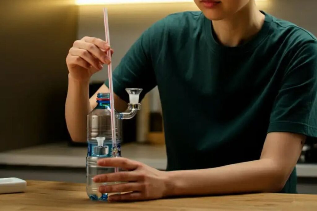 ペットボトルにガラス製の喫煙具を装着し、ストローを挿入している人物